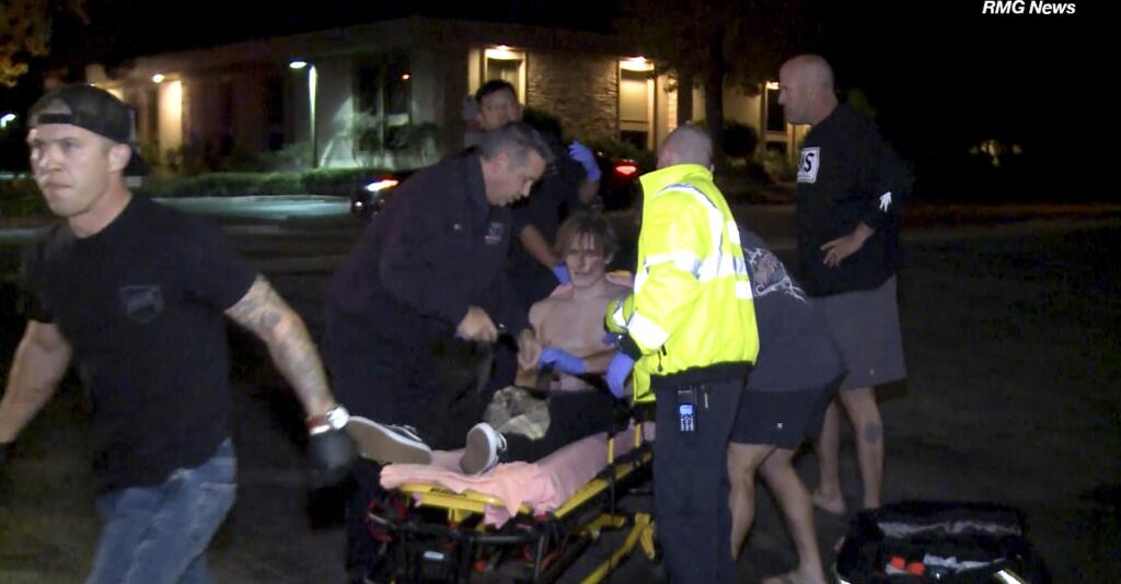 In this image taken from video a victim is treated near the scene of a shooting, Wednesday evening, Nov. 7, 2018, in Thousand Oaks, Calif. A hooded gunman dressed entirely in black opened fire on a crowd at a country dance bar holding a weekly 'college night' in Southern California, killing multiple people and sending hundreds fleeing including some who used barstools to break windows and escape, authorities said Thursday. The gunman was later found dead at the scene. (RMG News via AP)