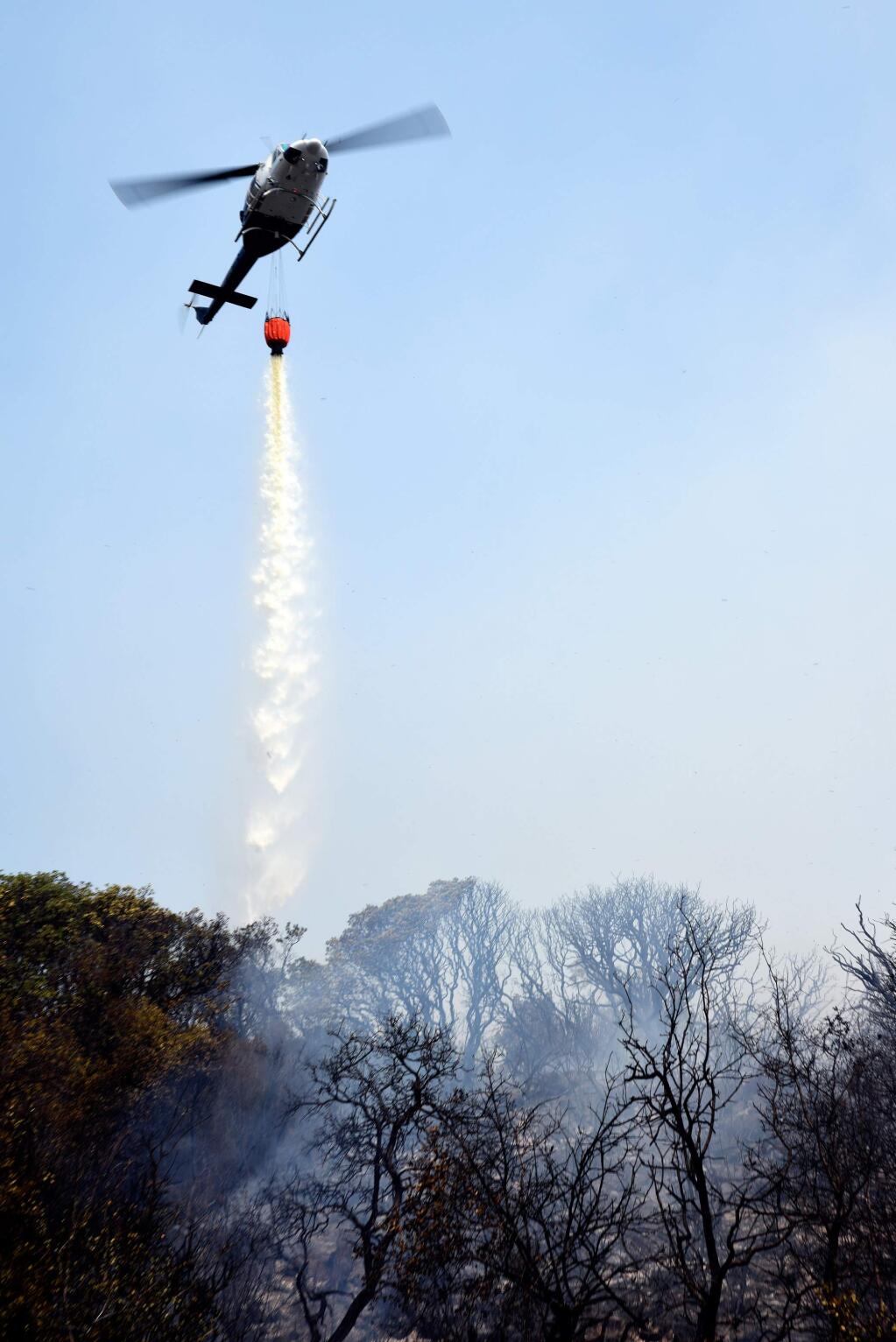 A firefighting helicopter drops water on a burning area along Morgan Valley Road during the fourth day battling the Rocky Fire near Clearlake Oaks, California on Saturday, August 1, 2015. The Rocky Fire to date has burned approximately 22,500 acres and is only 5% contained. (Alvin Jornada / The Press Democrat)