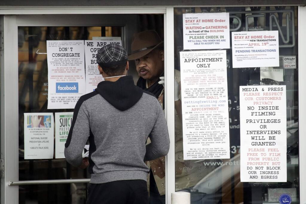 An employee answers questions at the entrance to a gun shop Tuesday, March 24, 2020, in Culver City, Calif. (AP Photo/Marcio Jose Sanchez)