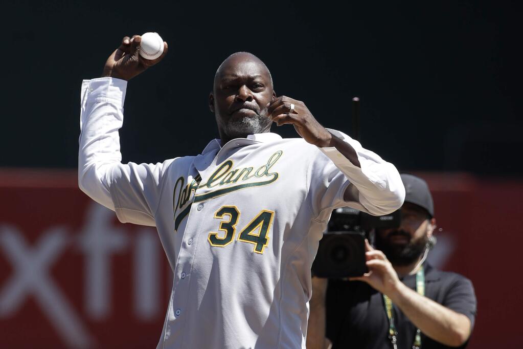 Former Oakland Athletics player Dave Stewart throws out the ceremonial first pitch before a game between the Athletics and the San Francisco Giants in Oakland, Sunday, Aug. 25, 2019. (AP Photo/Jeff Chiu)