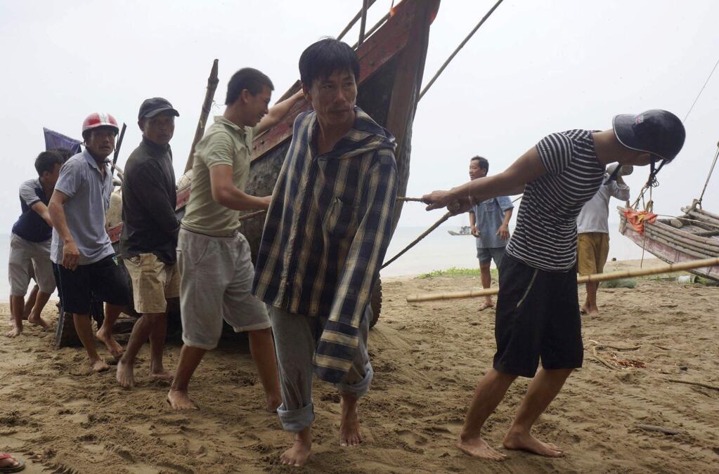 Vietnamese villagers move a fishing boat on shore in northern Thanh Hoa province, Vietnam, Thursday, Sept. 14, 2017. Vietnam on Thursday was bracing for typhoon Doksuri, which is expected to be the most powerful tropical cyclone to hit the Southeast Asian country in several years. (Trinh Duy Hung/Vietnam News Agency via AP)