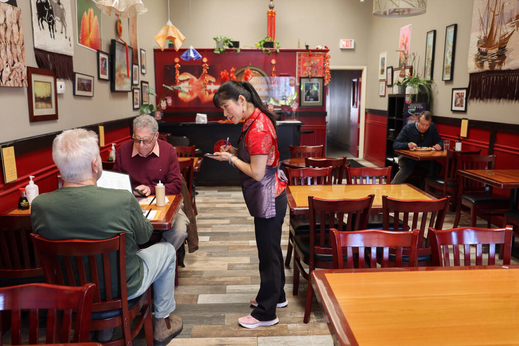 Aihe Fang, co-owner of Ting Hau Restaurant, right, takes down the lunch orders of Alan Silow and Jack Neureuter in Santa Rosa, Thursday, Jan. 26, 2023.  (Christopher Chung/The Press Democrat)