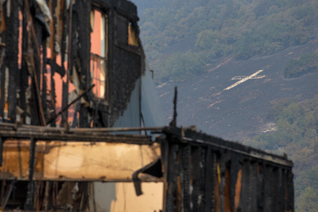 Santa Rosa's hillside cross is seen among burned and one of the burned homes on Mountain Hawk Drive after the Shady Fire, which is part of the larger Glass Incident, blazed into the Skyhawk community of Santa Rosa, California, on Tuesday, September 29, 2020. (Alvin A.H. Jornada / The Press Democrat)
