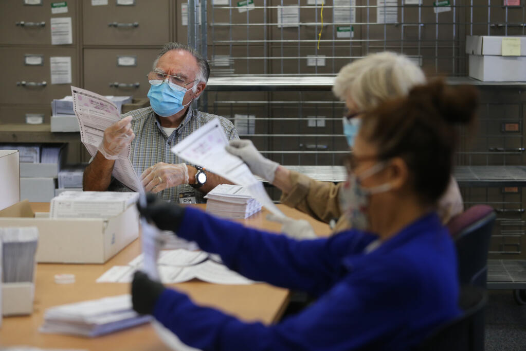 Extra help employee David Tatro checks for any potential problems with a ballot before it is run through the voting machine at the Sonoma County Registrar of Voters Office in Santa Rosa, Calif., on Monday, Sept. 13, 2021. (Beth Schlanker/The Press Democrat)