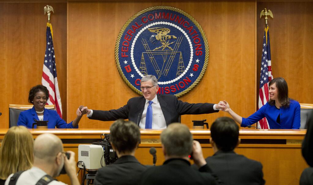 Federal Communication Commission (FCC) ChairmanTom Wheeler, center, joins hands with FCC Commissioners Mignon Clyburn, left, and Jessica Rosenworcel, before the start of their open hearing in Washington, Thursday, Feb. 26, 2015. (AP Photo/Pablo Martinez Monsivais)