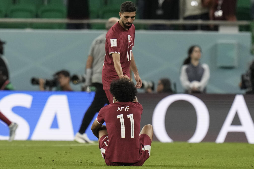 Qatar's Hassan Al-Haydos helps Akram Afif stand up after the World Cup group A soccer match between Qatar and Senegal, at the Al Thumama Stadium in Doha, Qatar, Friday, Nov. 25, 2022. Senegal won 3-1. (AP Photo/Hassan Ammar)