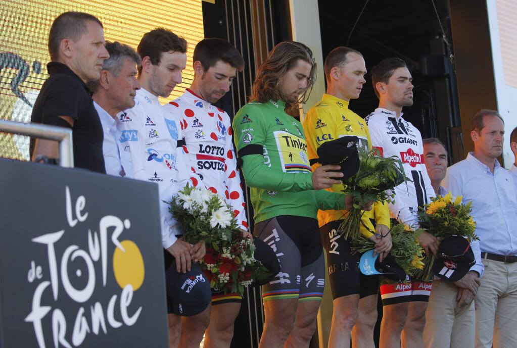 Britains Adam Yates, wearing the best young rider's white jersey, Belgiums Thomas de Gendt, wearing the best climber's dotted jersey, Peter Sagan of Slovakia, wearing the best sprinter's green jersey, Britain's Chris Froome, wearing the overall leader's yellow jersey, and Stage winner Netherlands Tom Dumoulin lay flowers after observing a minute of silence to commemorate the victims of the Nice truck attack on the podium the thirteenth stage of the Tour de France cycling race, an individual time trial over 37.5 kilometers (23 miles) with start in Bourg-Saint-Andeol and finish in La Caverne du Pont-d'Arc, France, Friday, July 15, 2016. A Frenchman of Tunisian descent drove a truck through crowds celebrating Bastille Day along Nice's beachfront, killing at least 84 people, many of them children. (AP Photo/Christophe Ena)