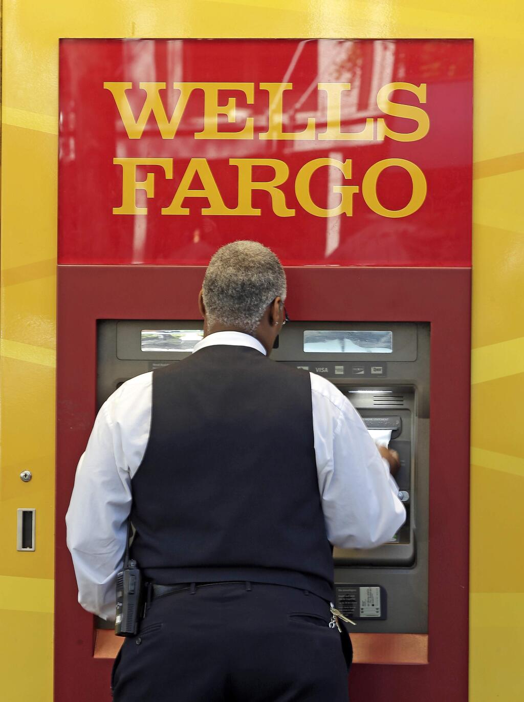 In this Thursday, April 13, 2017, photo, a man uses a Wells Fargo ATM in Charlotte, N.C. Wells Fargo & Co. reports earnings, Friday, July 14, 2017. (AP Photo/Chuck Burton)