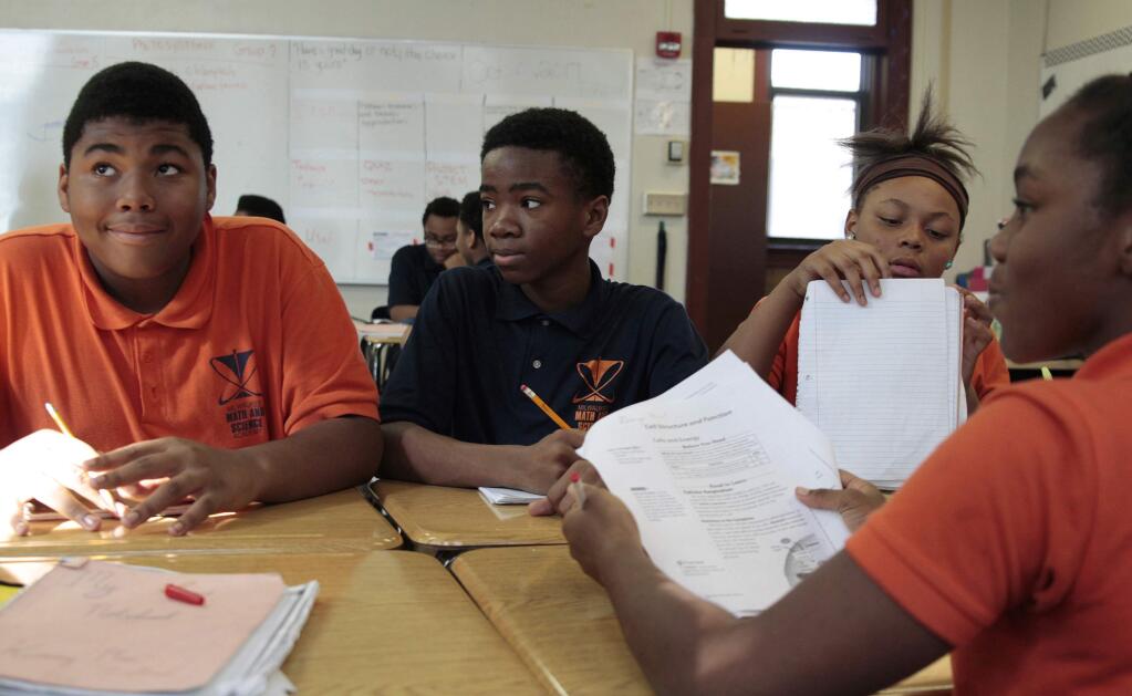 In this Oct. 20, 2017 photo, Jamain Lee, center, looks at classmate Andre'veon Mosby at Milwaukee Math and Science Academy, a charter school in Milwaukee. Next to him is classmate Dreamnoel Haynes, with Brianca Williams facing them. Lee has seen his grades improve since he enrolled two years ago from a school where he was bullied and frequently got into fights. (AP Photo/Carrie Antlfinger)