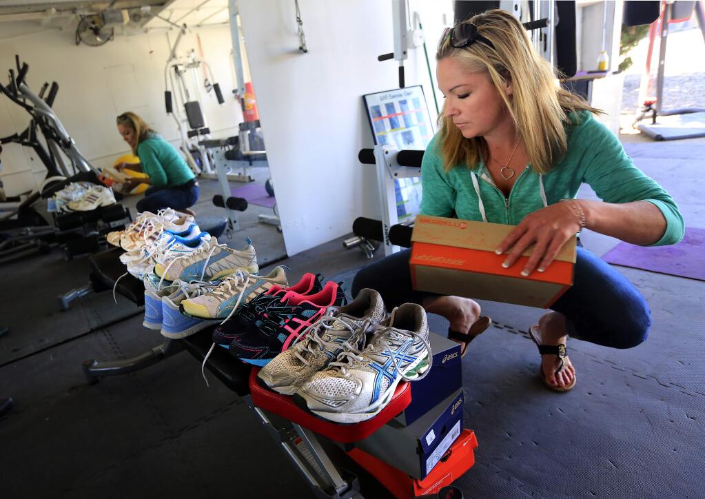 PHOTO: 2 by JOHN BURGESS / The Press Democrat -Gym teacher Myriah Volk stores donated athletic shoes in her Sebastopol home.