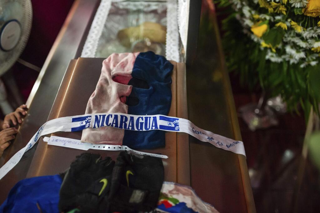 A ski mask adorns the coffin that contain the remains of Nicaraguan university student Gerald Vasquez who was fatally wounded when police forced students out of the National Autonomous University of Nicaragua, UNAN, in Managua, Saturday, July 14, 2018. Students sought refuge in a local church after police forced them out of the UNAN, resulting in a tense Friday night of armed attacks that left two dead and dozens wounded. (AP Photo/Cristobal Venegas)