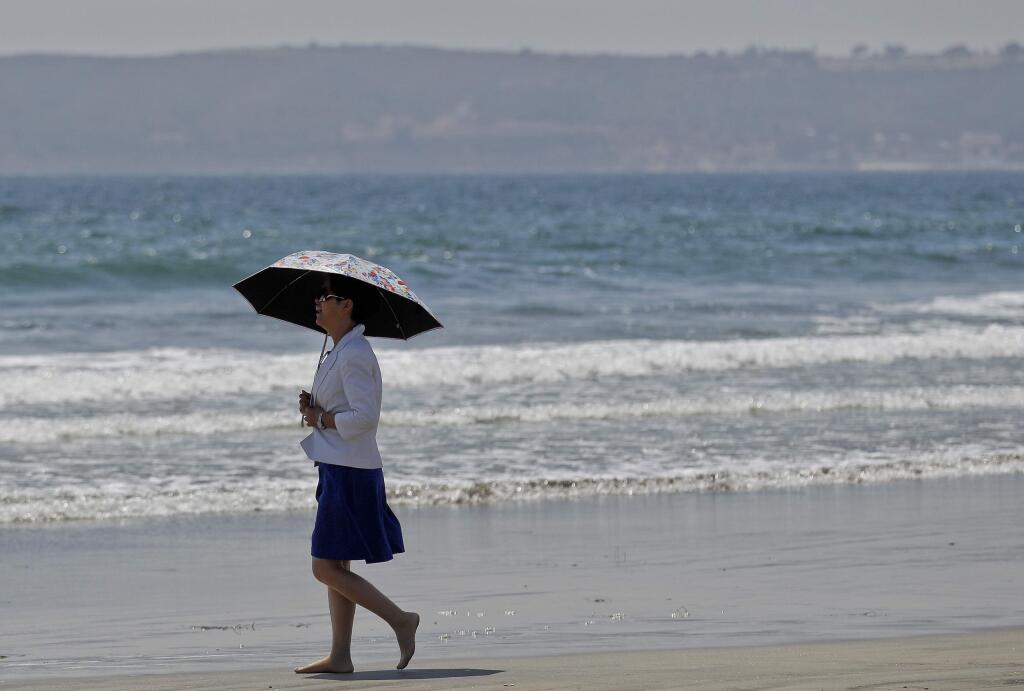 FILE - In this May 22, 2012 file photo, a woman walks barefoot along the Coronado Beach in Coronado, Calif. Authorities say 35 beachgoers have been stung by stingrays in San Diego County. People wading in the Pacific Ocean encountered the rays throughout the day Thursday, July 28, 2016, in Coronado. (AP Photo/Lenny Ignelzi, File)