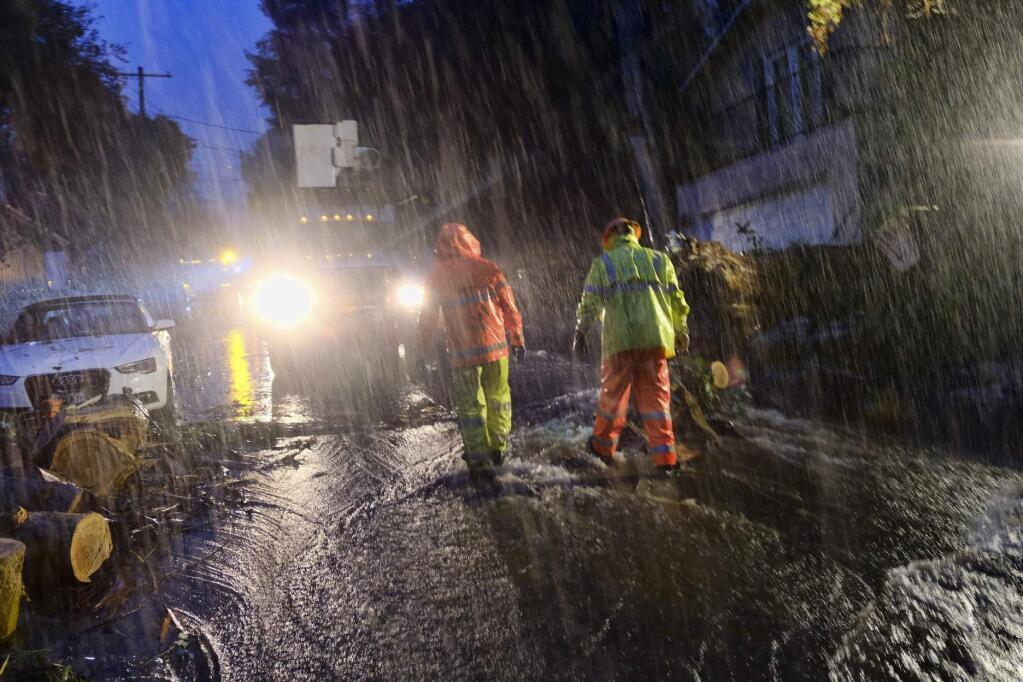 Department of Water and Power employees work in the pouring rain to clear a fallen tree from a road in the Hollywood hills in Los Angeles, Thursday, Jan. 17, 2019. The latest in a series of Pacific Ocean storms pounded California with rain and snow Thursday, prompting officials to put communities on alert for mudslides and flooding and making travel treacherous. (AP Photo/Richard Vogel)