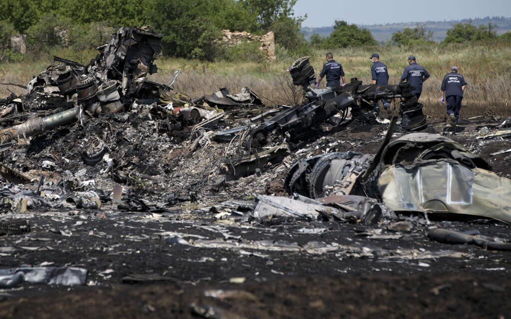 Ukrainian emergency workers walk by charred debris at the crash site of Malaysia Airlines Flight 17 near the village of Hrabove, eastern Ukraine, Sunday, July 20, 2014. (AP Photo/Vadim Ghirda)