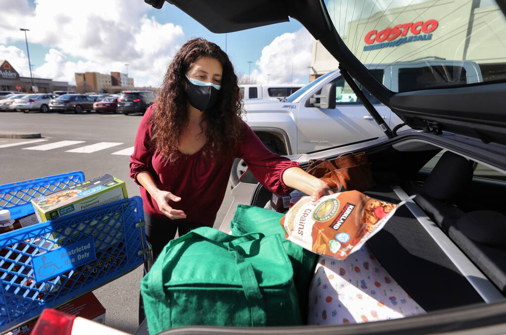 Sienna Hornback packs her groceries into her car at Costco in Rohnert Park on Tuesday, February 2, 2021.  Hornback decided to wear two masks for added protection against the coronavirus and its new variants.  (Christopher Chung/ The Press Democrat)