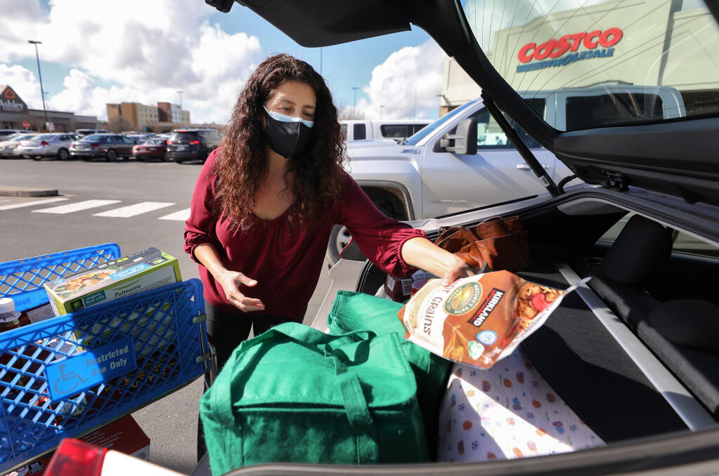 Sienna Hornback puts her groceries into her car at Costco in Rohnert Park on Tuesday, Feb. 2, 2021. Hornback decided to wear two masks for added protection against the coronavirus and its new variants. (Christopher Chung / The Press Democrat)