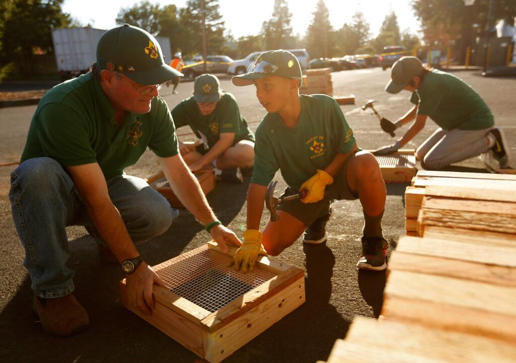 Troop 32 assistant scoutmaster Brett Carver, left, helps boy scout Cooper Ramnarine, 11, finish off the frame of a sifting box, at Amy's Kitchen in Santa Rosa, California on Thursday, October 1, 2015. The Scouts are building 4,000 sifting boxes for families affected by the Valley Fire to sift through the ashes of their homes in hopes of finding valuables or other small items that may have survived the fire. (Alvin Jornada / The Press Democrat)