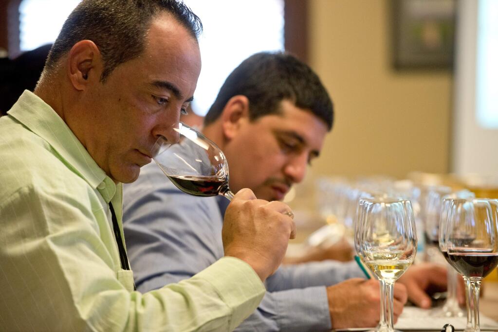 Juan Manuel Betancor Tejera, left, president of Balcon del Habano Varadero takes in the aroma of a Gloria Ferrer pinot noir while Sommelier Joel Francisco Chacon Valdes of Casa Del Habano writes down notes of the wines during a tasting at Gloria Ferrer Winery with the Cuban Sommelier Summit in Sonoma on July 22, 2014. (Alvin Jornada / For The Press Democrat)