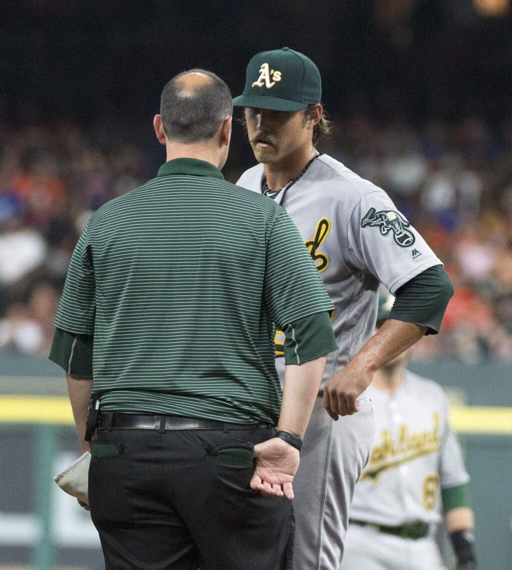 Oakland Athletics starting pitcher Daniel Mengden talks with a trainer after being hit by a ball during the fourth inning of a baseball game against the Houston Astros, Friday, July 8, 2016, in Houston. (AP Photo/George Bridges)