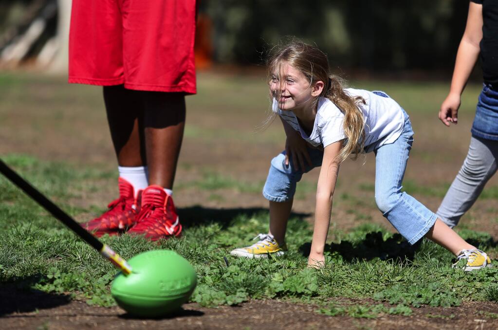 Second-grader Alexis Keller lines up in a three-point stance while players from the SRJC football team coach kids through drills at Proctor Terrace School, in Santa Rosa, on Friday, October 2, 2015. (Christopher Chung/ The Press Democrat)