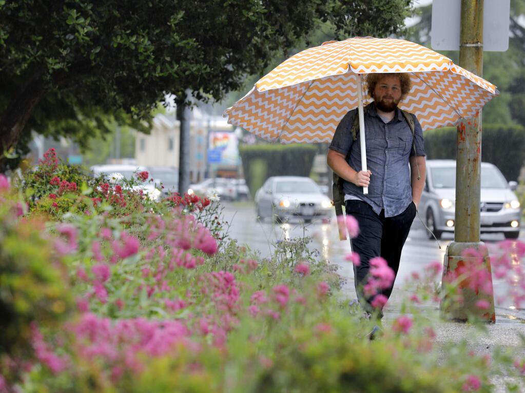 Jack Lupin uses a beach umbrella to stay dry as he walks down Santa Rosa Avenue in Santa Rosa on Wednesday, May 15, 2019. (BETH SCHLANKER/ PD)