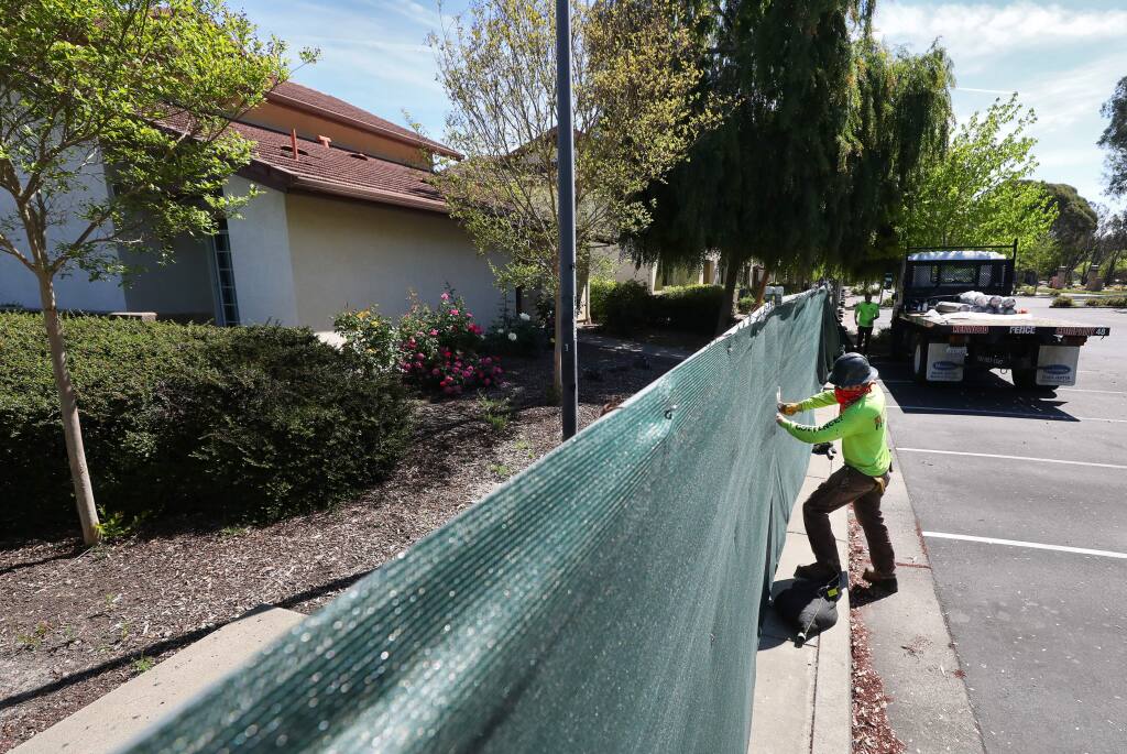 John Rainwater, with Kenwood Fence Co., works on attaching privacy screening onto a fence around the Sauvignon Village residence halls, on the Sonoma State University campus in Rohnert Park on Monday, April 27, 2020. (Christopher Chung/ The Press Democrat)