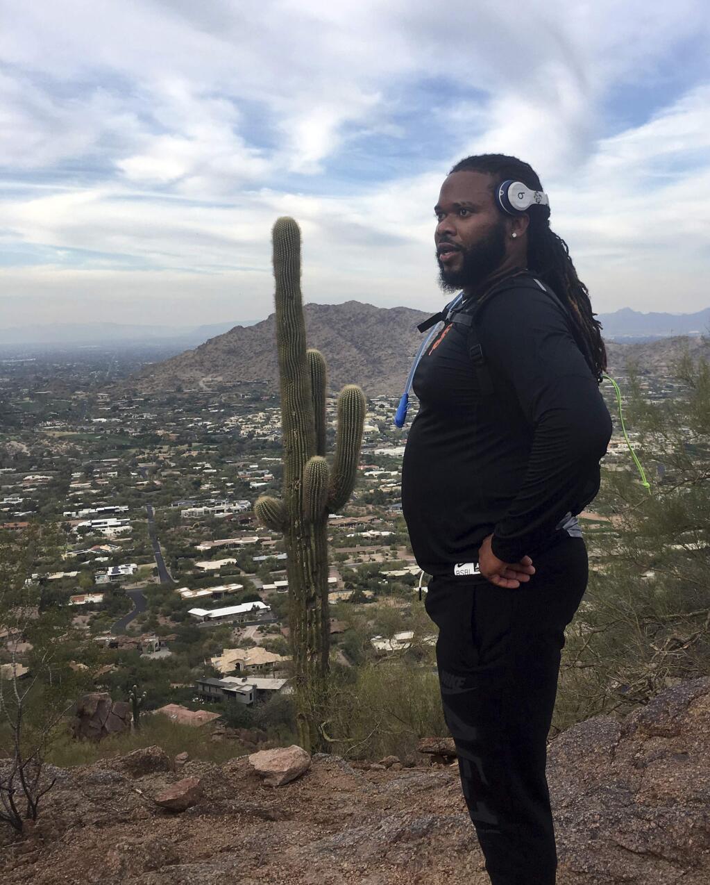 In this photo from Thursday, Feb. 15, 2018, San Francisco Giants pitcher Johnny Cueto stands atop Camelback Mountain in Scottsdale, Ariz. In each of his three springs with San Francisco, Cueto has picked a rental home nearby Camelback, on a different side of the idyllic landmark every year to be close by his favorite hiking terrain. (AP Photo/Janie McCauley)