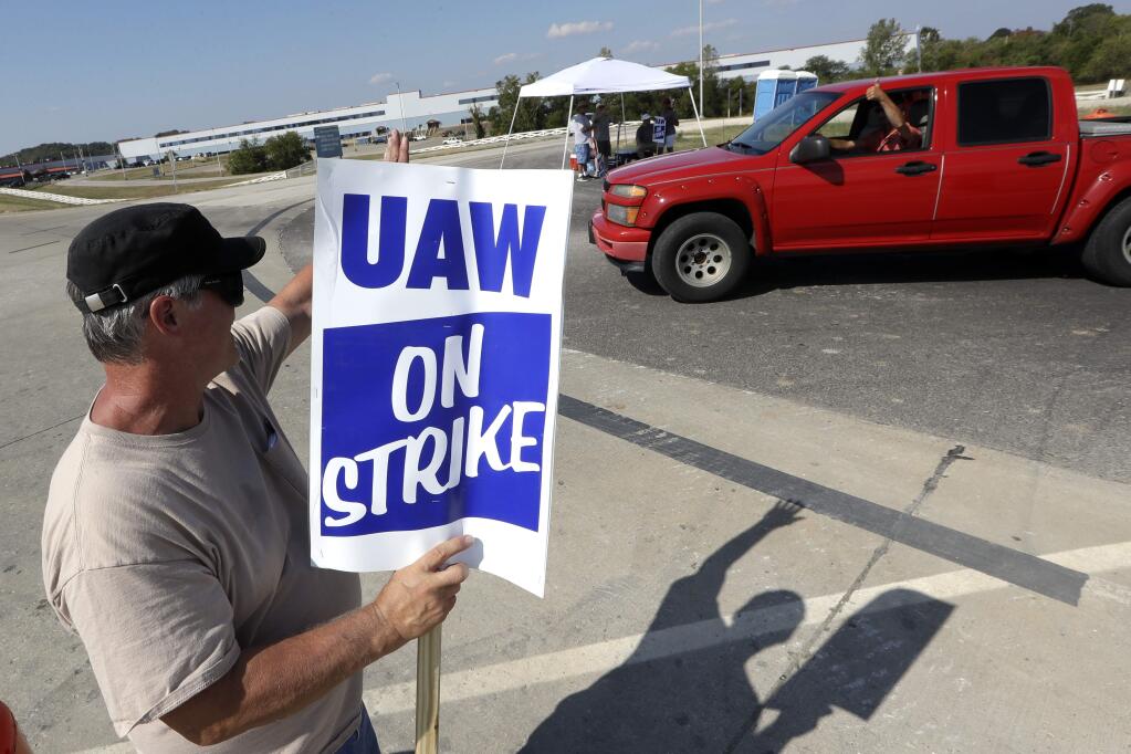 James Hatfield waves to a passing driver as he pickets outside the General Motors plant in Spring Hill, Tenn., Monday, Sept. 16, 2019. More than 49,000 members of the United Auto Workers walked off General Motors factory floors or set up picket lines early Monday as contract talks with the company deteriorated into a strike. (AP Photo/Mark Humphrey)