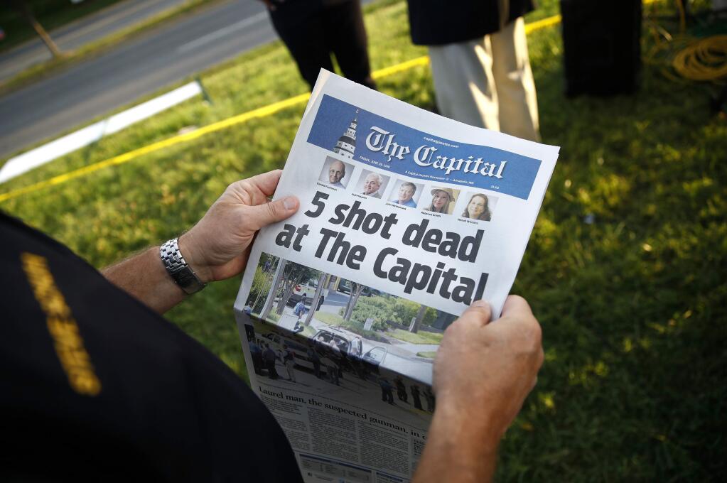 Steve Schuh, county executive of Anne Arundel County, holds a copy of The Capital Gazette near the scene of a shooting at the newspaper's office, Friday, June 29, 2018, in Annapolis, Md. (AP Photo/Patrick Semansky)