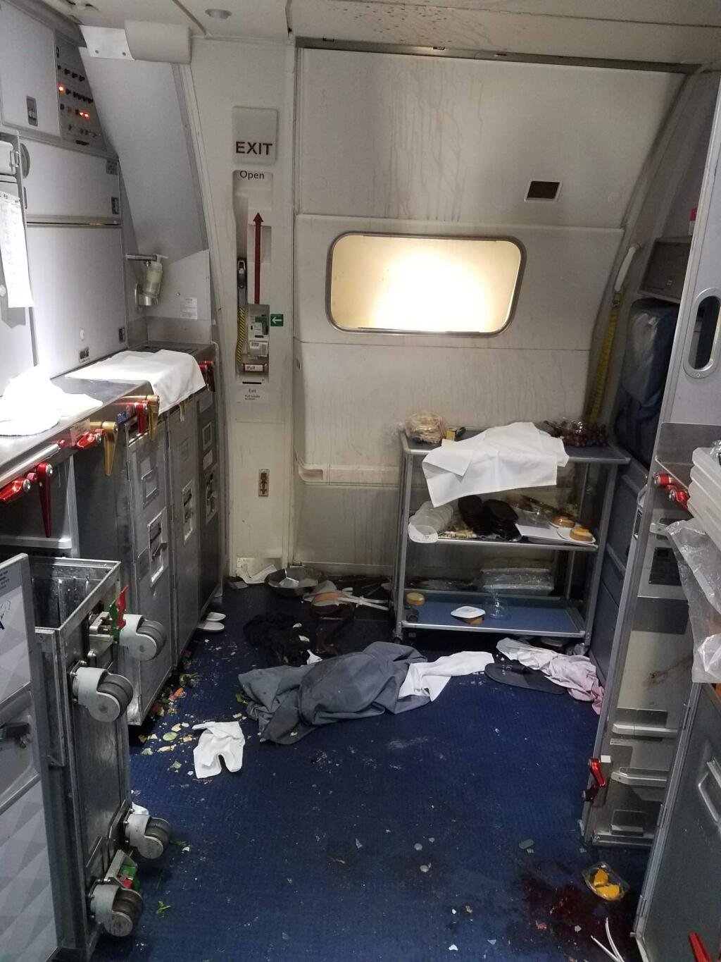 This Friday, July 7, 2017 photo taken the FBI and released via the U.S. Attorney's Office in Seattle shows the aftermath of a cabin on Delta Flight 129 from Seattle to Beijing, after authorities say flight attendants struggled with Joseph Daniel Hudek IV, a passenger who lunged for an exit door. The photo was included in a criminal complaint filed Friday, July 7. The passenger is charged with interfering with a flight crew and faces up to 20 years in prison. (FBI via U.S. Attorney's Office in Seattle via AP)