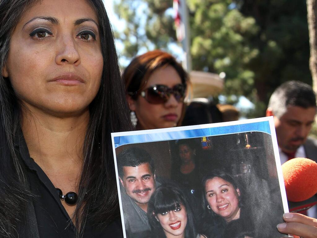 FILE - In this Oct. 2, 2014 file photo, attorney Claudia Osuna holds a photo of the Crespo family - from top left to bottom right, Bell Gardens, Calif., Mayor Daniel Crespo, his daughter Crystal, his wife Lyvette and son Daniel Crespo Jr., during a news conference in the Los Angeles surbuban city of Bell Gardens. A Los Angeles County grand jury has indicted Lyvette Crespo on a charge of voluntary manslaughter the shooting death of Daniel Crespo. The district attorney's office says Lyvette Crespo pleaded not guilty Thursday, April 23, 2015, during an arraignment at which the indictment was unsealed. The 45 year-old mayor was fatally shot at his home on Sept. 30, 2014. (AP Photo/Nick Ut, File)