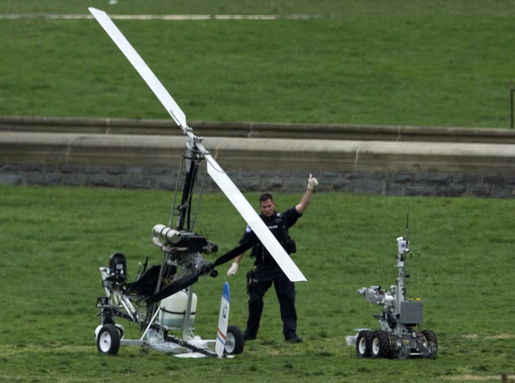 A Capitol Police officer flashes a thumbs up after inspecting the small helicopter a man landed on the West Lawn of the Capitol in Washington, Wednesday, April 15, 2015. Police arrested a man who steered his tiny, one-person helicopter onto the West Lawn of the U.S. Capitol Wednesday, astonishing spring tourists and prompting a temporary lockdown of the Capitol Visitor Center. Capitol Police didn't immediately identify the pilot or comment on his motive, but a Florida postal carrier named Doug Hughes took responsibility for the stunt on a website where he said he was delivering letters to all 535 members of Congress in order to draw attention to campaign finance corruption. (AP Photo/Manuel Balce Ceneta)