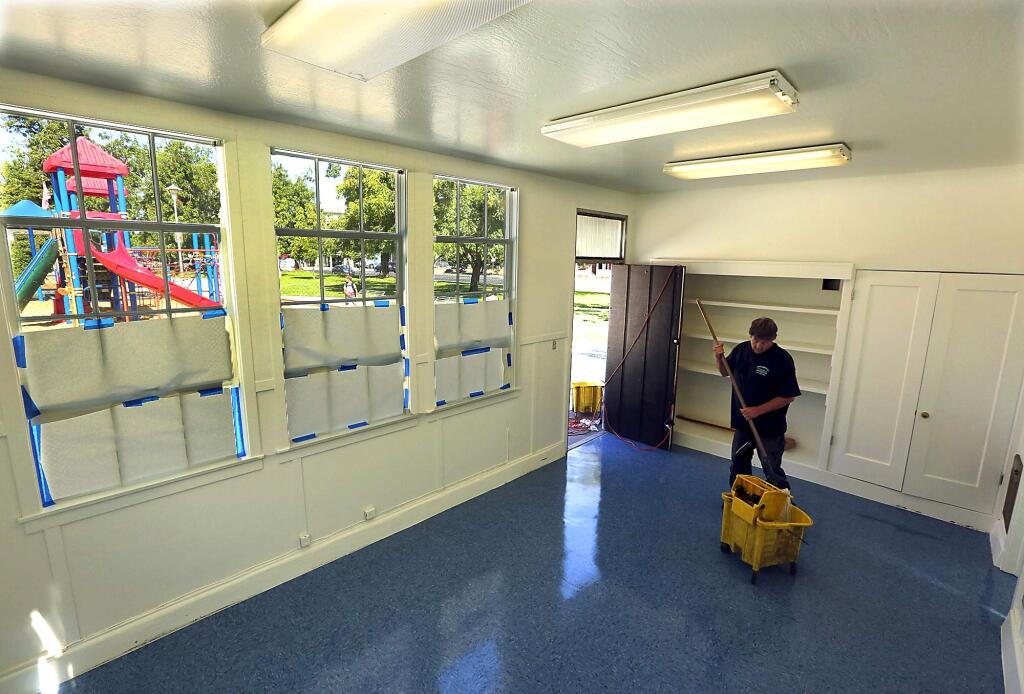 Kevin Freeman applies the final coat of floor sealant to an old storage building that will serve as an office for police to increase their presence in Walnut Park in Petaluma. (JOHN BURGESS/The Press Democrat)