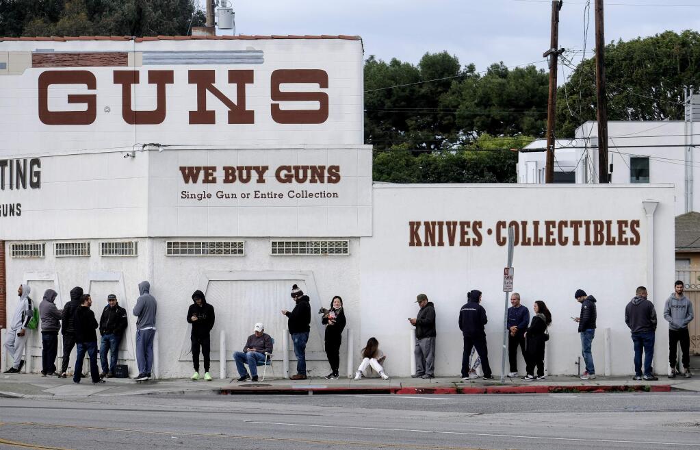 FILE - In this March 15, 2020, file photo, people wait in line to enter a gun store in Culver City, Calif. Los Angeles County Sheriff Alex Villanueva, who was sued by gun-rights groups after trying to shut down firearms dealers in the wake of coronavirus concerns, said Monday, March 30, that he is abandoning the effort. (AP Photo/Ringo H.W. Chiu, File)