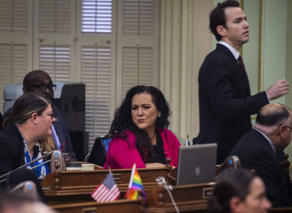 Assemblywoman Lorena Gonzalez, D-San Diego, talks with other assembly members on the Assembly floor at the Capitol in Sacramento, Calif., on Thursday, Feb. 27, 2020, as Assemblyman Kevin Kiley, R-Rocklin, walks past her. Gonzalez has proposed an amendment to Assembly Bill 5 - which requires many independent contractors to be re-classified as employees with benefits - that removes the submission cap but also mandates that freelancers cannot replace regular employees. (Daniel Kim/The Sacramento Bee via AP)