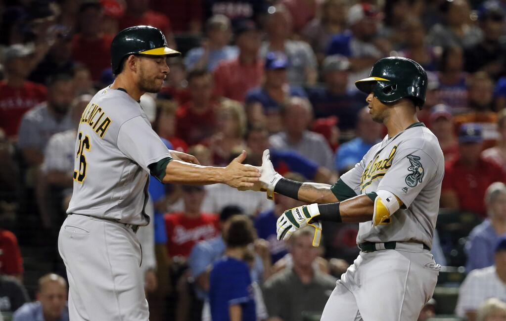 Oakland Athletics' Danny Valencia, left, and Khris Davis, right, celebrate Davis'two-run home run that scored them in the fourth inning of a baseball game against the Texas Rangers, Friday, Sept. 16, 2016, in Arlington, Texas. (AP Photo/Tony Gutierrez)