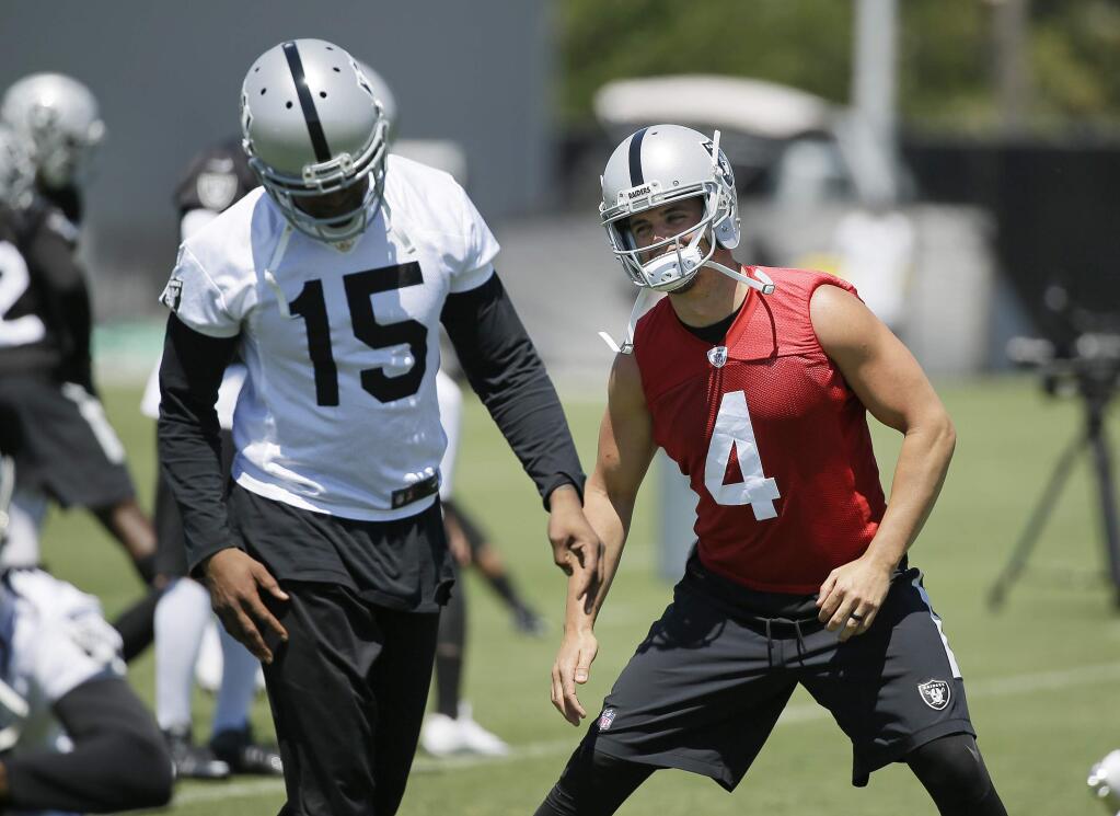 Oakland Raiders quarterback Derek Carr (4) stretches by wide receiver Michael Crabtree, (15) during an NFL football team activity Tuesday, May 23, 2017, in Alameda, Calif. (AP Photo/Eric Risberg)