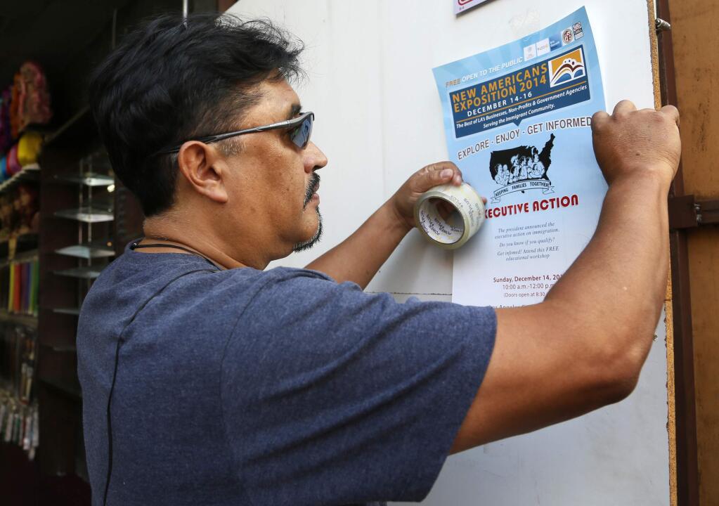 This Dec. 10, 2014 photo shows Tony Bernabe posts a flier in downtown Los Angeles advertising a massive information session scheduled for this weekend to tell immigrants more about President Barack Obamas executive actions on immigration. Immigrant advocates have been holding workshops in churches, schools and meeting rooms across the country to dispel rumors, ward off fraud and help immigrants here illegally determine if they qualify to apply for a work permit and protection from deportation. (AP Photo/Nick Ut)