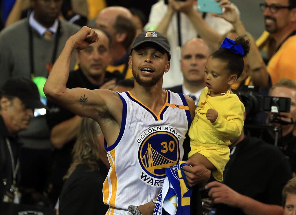 Stephen Curry celebrates with his daughter after the Warriors' 129-120 victory against the Cavaliers to claim the NBA crown in Game 5 of the NBA Finals, Monday, June 12, 2017 in Oakland. (Kent Porter / The Press Democrat)