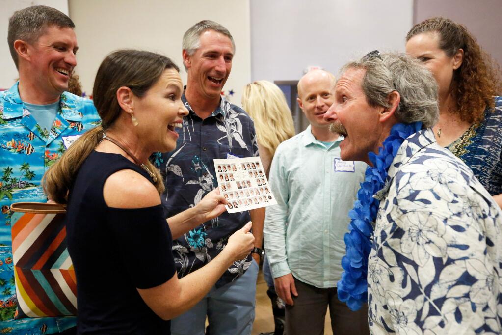 Jim Boyce, right, shows his surprise as his former student Catherine Green gives him a copy of her class picture of the 1983-1984 fifth grade class at St. John Catholic School. Boyce's copy of the photo was destroyed in the Tubbs fire. (Alvin Jornada / The Press Democrat)