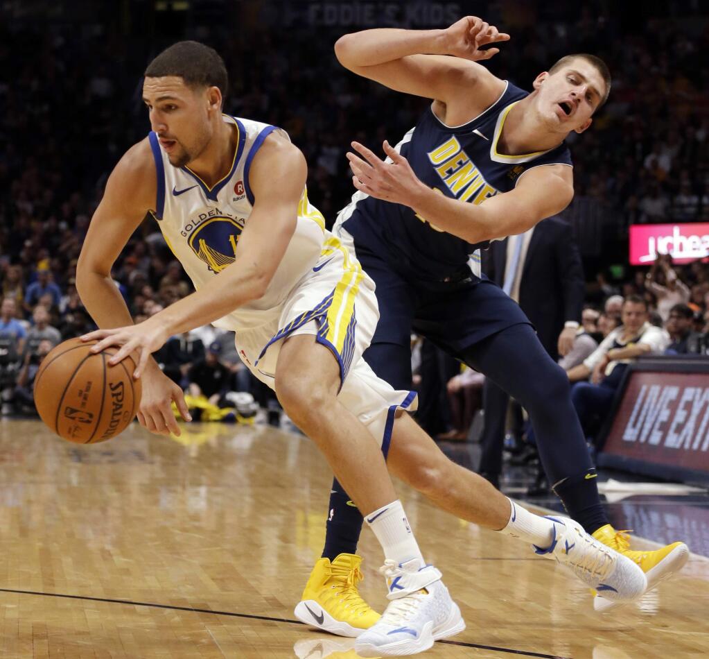 Golden State Warriors guard Klay Thompson (11) drives past Denver Nuggets center Nikola Jokic (15) during the second quarter of an NBA basketball game Saturday, Nov. 4, 2017, in Denver. (Photo by Jack Dempsey)