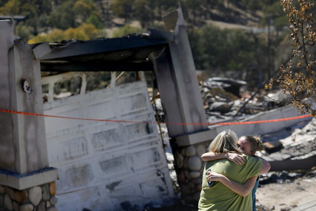 Leslie Wood, right, who's home survived the fire, gives her neighbor Eve Herdell, left, a hug at the Herdell home on Indian Rock Rd on Sunday, September 20, 2015 in Hidden Valley Lake, California . (BETH SCHLANKER/ The Press Democrat)