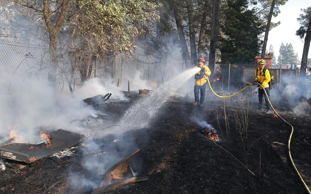 Sonoma County Fire District Captain Aron Levin, left, and firefighter Tim Rohrer work on putting out a fire north of Precision Crane Service, Inc., between Highway 101 and Conde Lane, in Windsor on Wednesday, August 21, 2019. (Christopher Chung/ The Press Democrat)