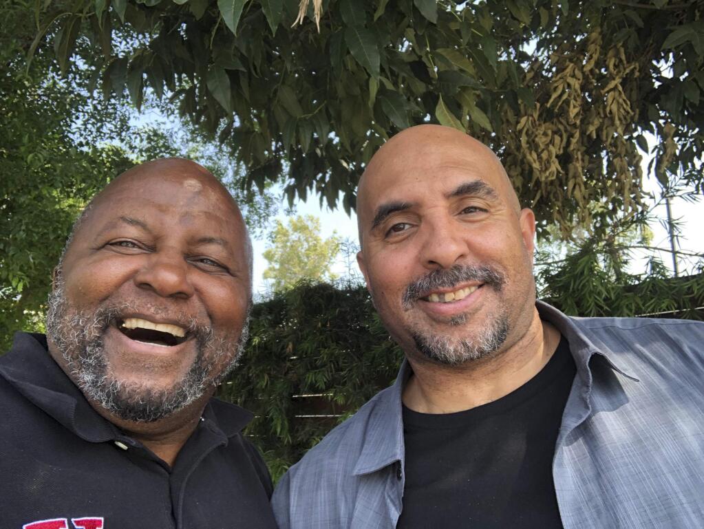 This photo provided by Mayer Brown LLP shows Kenneth Oliver, right, after his release from prison, posing for a selfie with his father Dr. Bernard Oliver on Tuesday, June 4, 2019. Kenneth Oliver, a California man, has been freed from prison after serving 23 years of his life sentence on a joyriding conviction. It included eight years in solitary confinement for possessing a book written by the co-founder of a notorious prison gang. (Bernard Oliver/Mayer Brown LLP via AP)