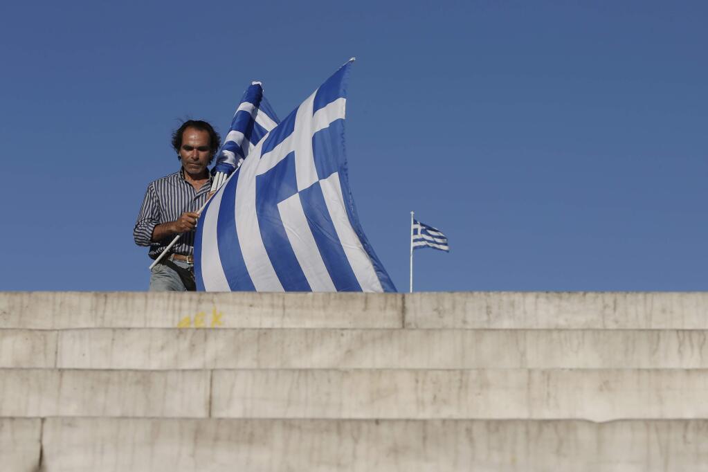 A vendor sells Greek flags walks at Syntagma square in Athens, Sunday, July 5, 2015. (AP Photo/Petros Giannakouris)