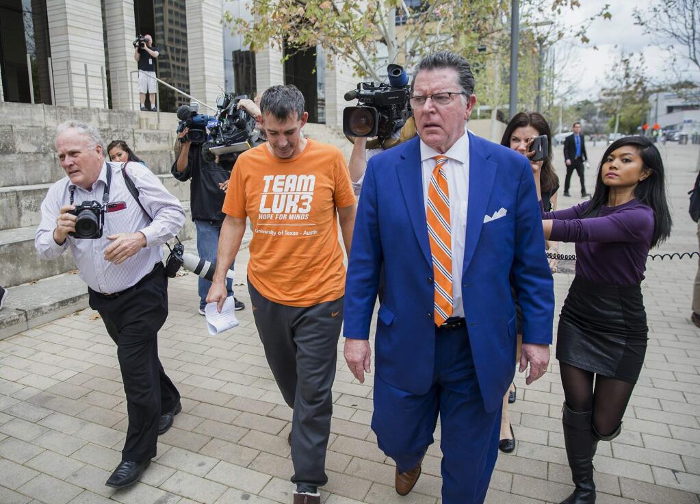 Texas men's tennis coach Michael Center, center left, walks with defense lawyer Dan Cogdell, center right, away from the federal courthouse in Austin, Texas, Tuesday, March 12, 2019. Center is among a few people in the state charged in a scheme that involved wealthy parents bribing college coaches and others to gain admissions for their children at top schools, federal prosecutors said Tuesday. (Ricardo B. Brazziell / AP)