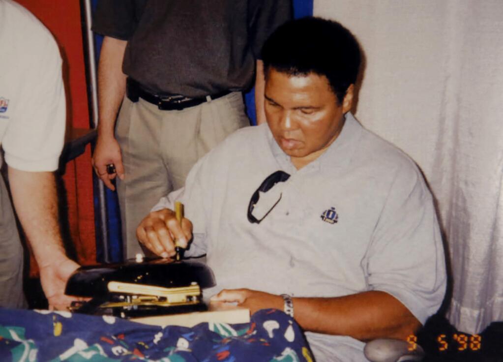 Muhammad Ali signs a boxing bell on August 5, 1998. (Courtesy of Rob Hemphill)