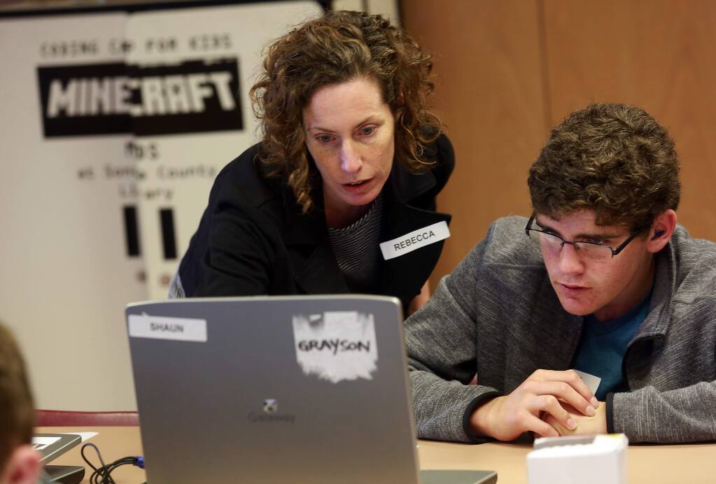 Rebecca Forth shows Shaun Brynes, 13, how to create a new ore at the Minecraft Coding Camp at the Healdsburg Public Library on Saturday. (Photo by John Burgess/The Press Democrat)
