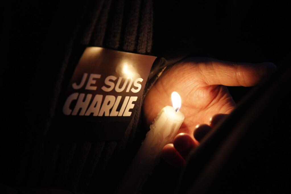 A man holds a candle and a sticker reading ' I am Charlie', during a demonstration in Paris, Wednesday, Jan. 7, 2015. Three masked gunmen shouting 'Allahu akbar!' stormed the Paris offices of a satirical newspaper, Charlie Hebdo, Wednesday, killing 12 people, including its editor, before escaping in a car. It was France's deadliest postwar terrorist attack. (AP Photo/Christophe Ena)