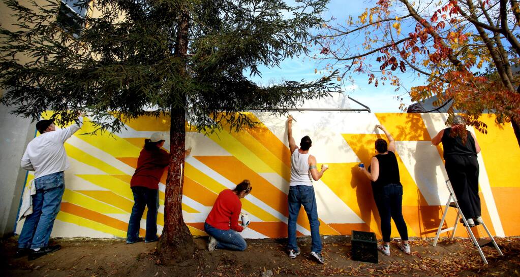 Volunteers paint a mural on a wall next to the Redwood Gospel Mission in Santa Rosa, Wednesday, November 26, 2014. (Crista Jeremiason / The Press Democrat)